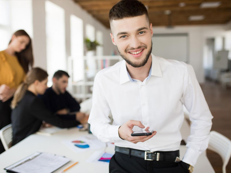 Ragazzo dai capelli corti sorride e ha uno smarphone in mano con l'applicazione intranet mobile app di lolyo attiva
